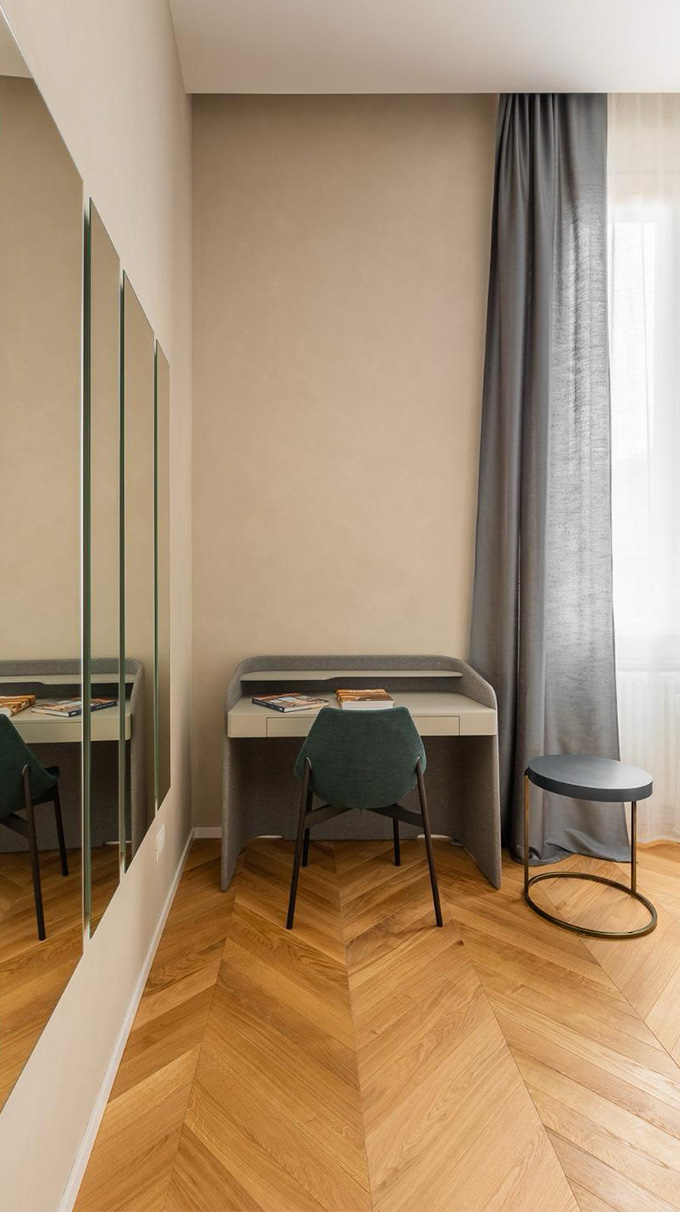 Angolo studio elegante in camera B&B con scrittoio, sedia imbottita, specchi a parete, pavimento in legno e arredi Pianca Contract.
