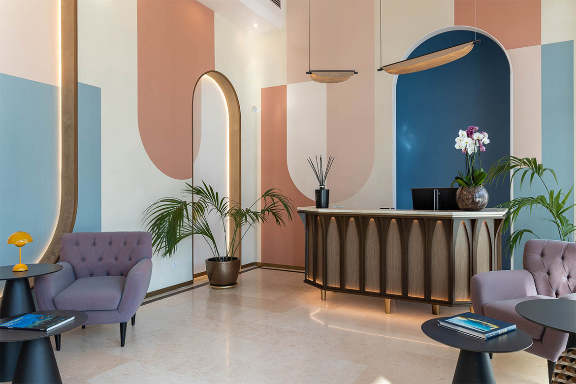 Reception moderna in DoubleTree Hilton a Firenze con bancone in legno, pareti decorative colorate, poltrone imbottite, tavolini neri e arredi Pianca Contract.