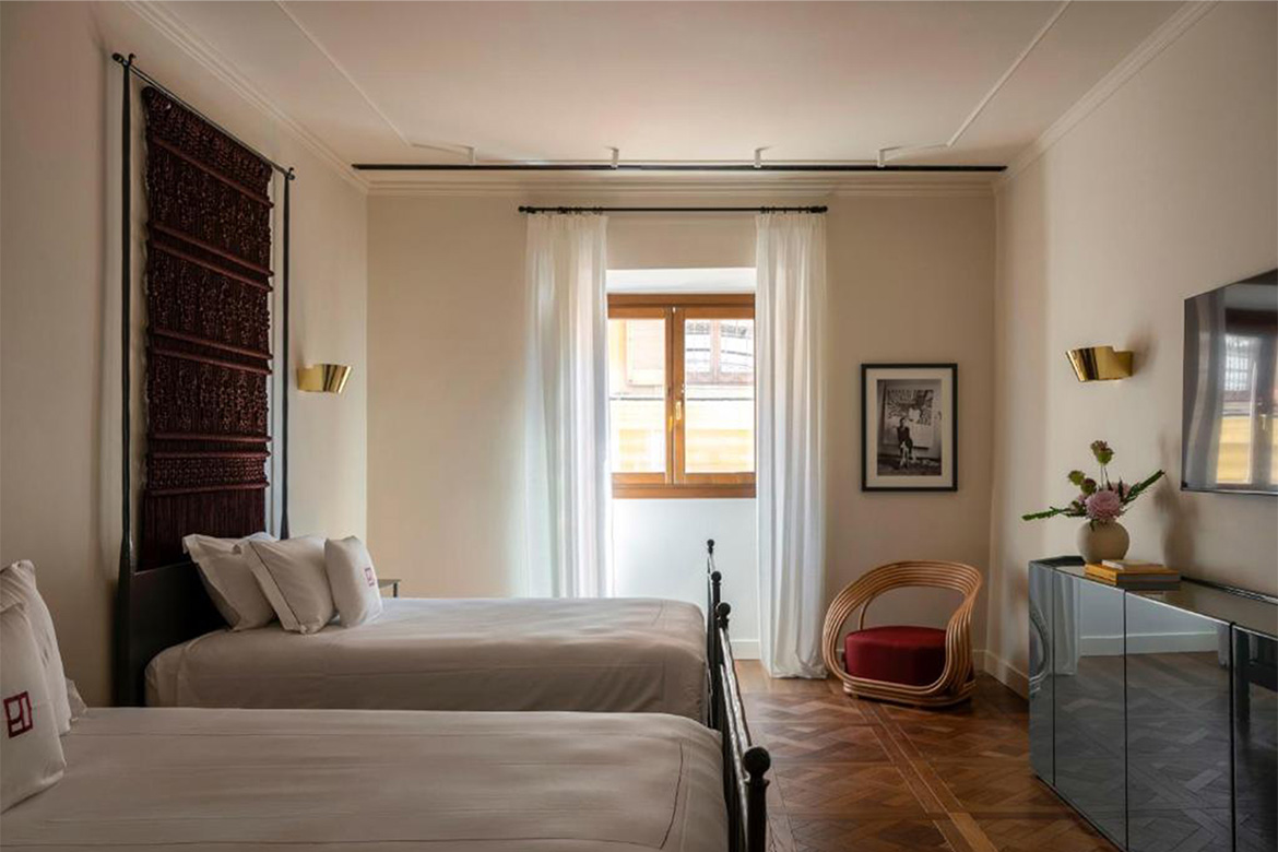 Camera doppia elegante in Hotel Talia a Roma con letti singoli, pavimento in legno, poltrona decorativa, mobile contenitore e arredi Pianca Contract.